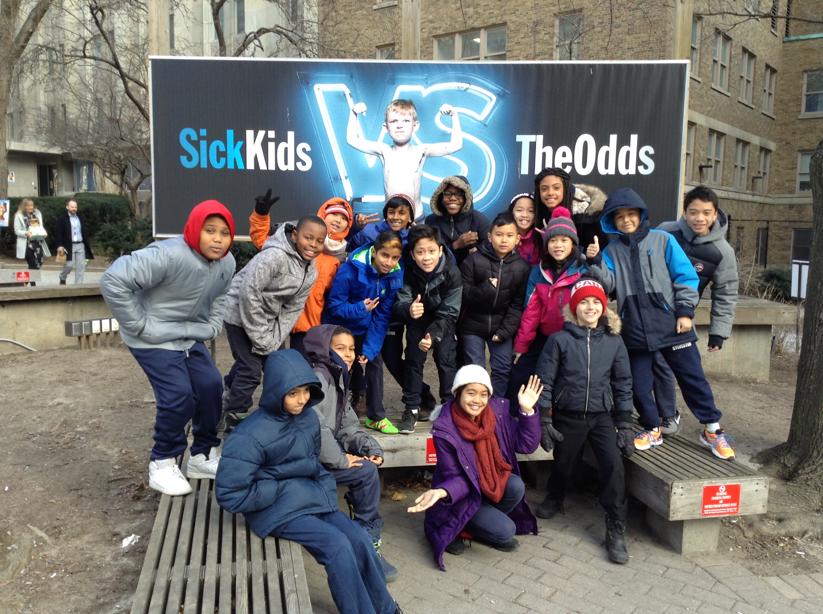 Children posing in front of SickKids' billboard