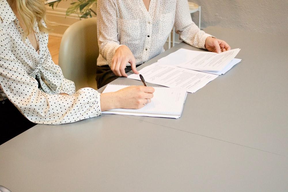 Foto de duas mulheres assinando documentos em assistência jurídica