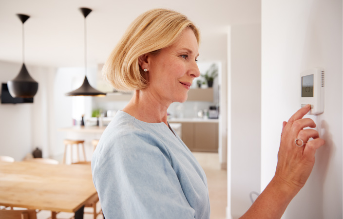 A woman turning down her thermostat before going on vacation