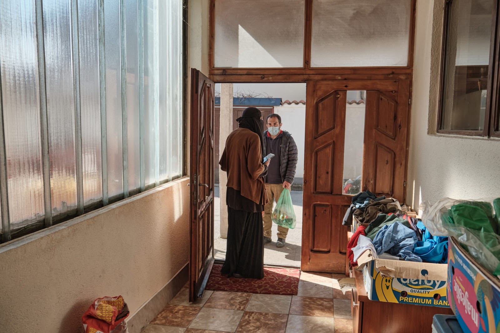 Azra chats with a man who came to her house to get food and clothes for himself and his family. | Photo: Chiara Fabbro