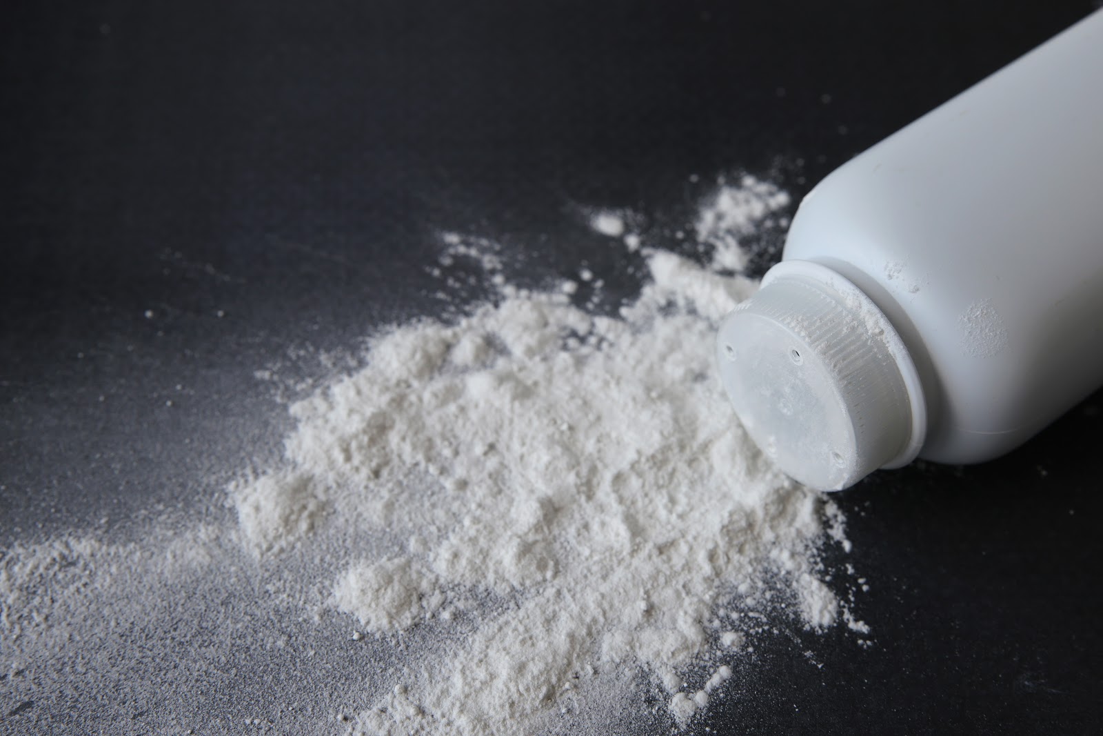 A bottle of baby powder on its side spilling powder out