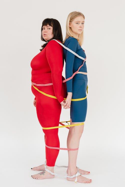 Sporty women with different bodies covered with measuring tapes