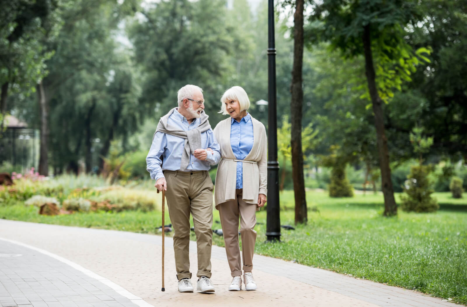 Happy senior couple talking while walking outside a Senior Living Community.