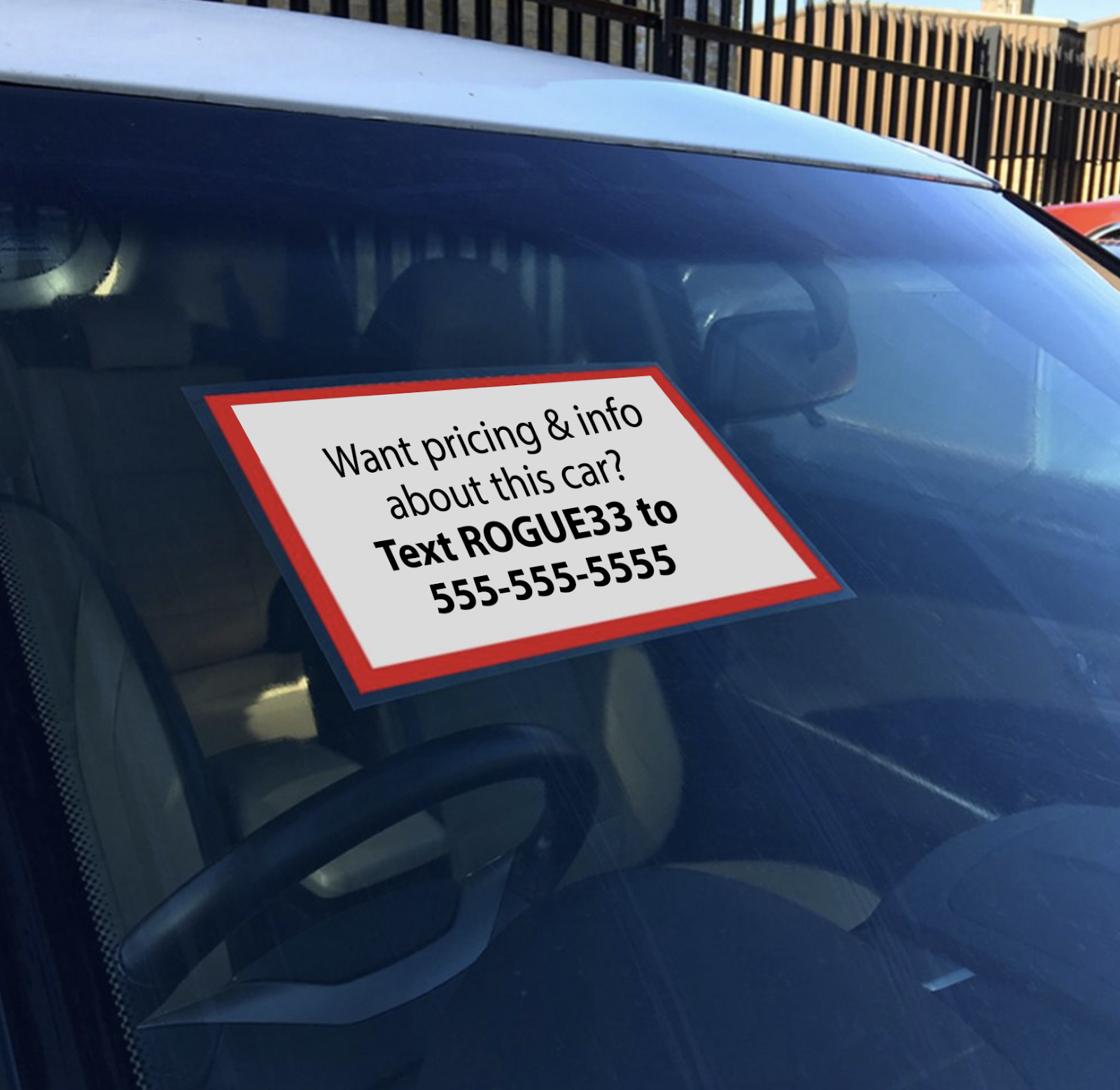 sign on car window that says "Want pricing & info about this car? Text ROGUE33 to 555-555-5555"