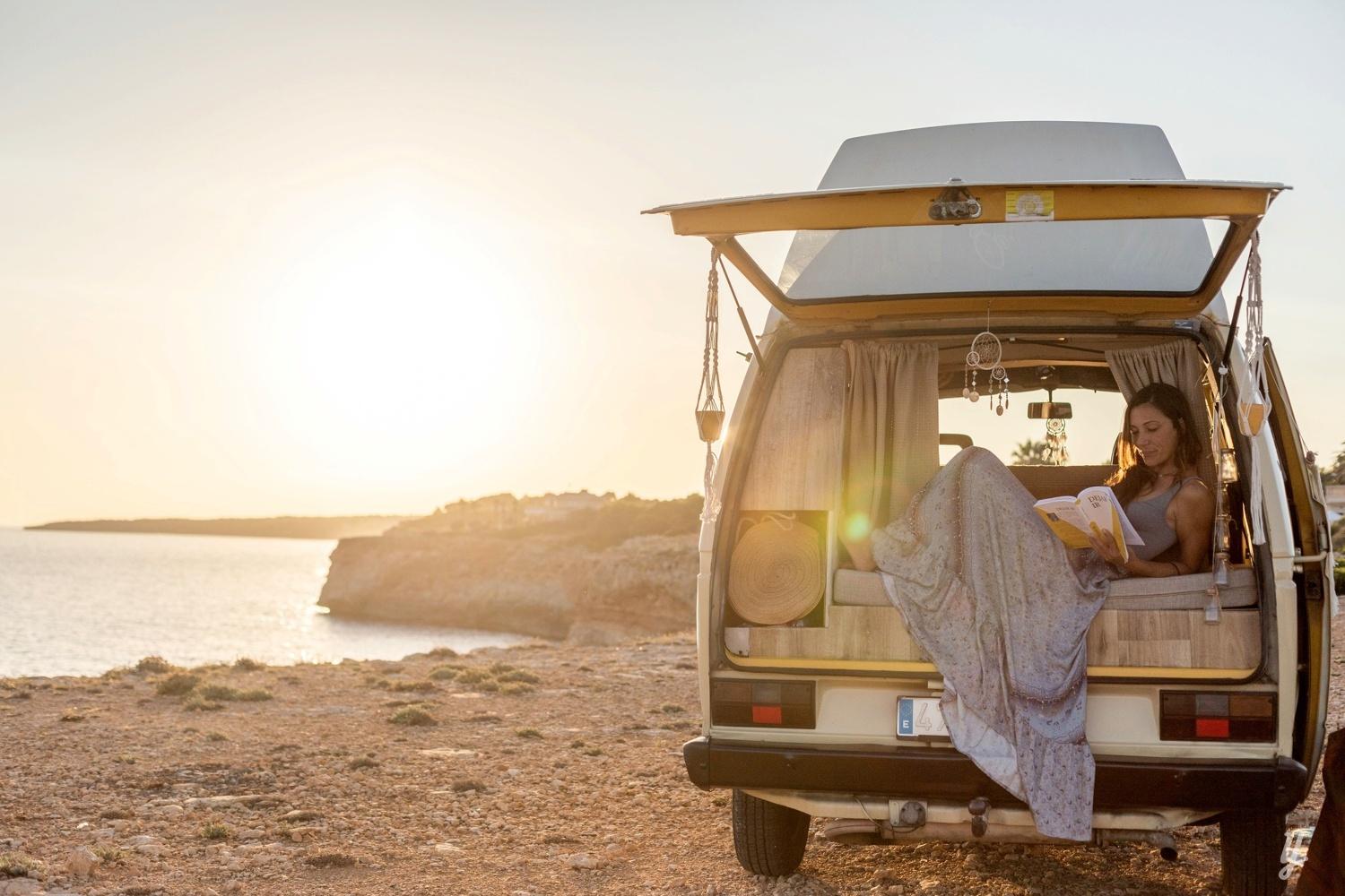 girl sitting in camper van on beach