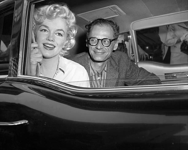 Arthur Miller, the playwright, gazes` adoringly at his wife, Marilyn Monroe, as they drive away from Lenox HIll Hospital. The dazzling film star was...