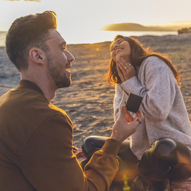 Young man making proposal to woman on sandy sea shore Free Photo