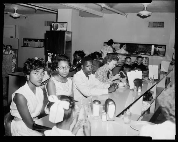 Photograph of Carolyn House, Brenda Officer, Paul Anderson, and other people at an African American Civil Rights sit-in segregation protest at John A...