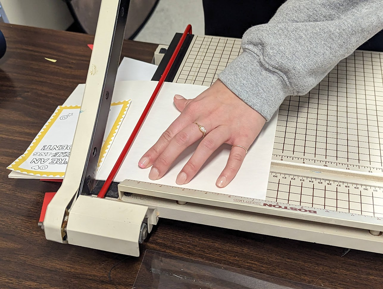 close-up photo of hands aligning paper in a paper cutter
