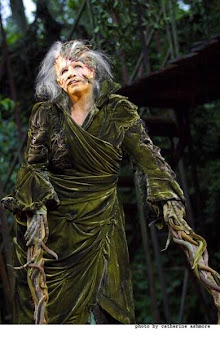 An actress wearing intensive stage makeup to look both old and sort of...tree-like? She has prosthetic tree branch arms.