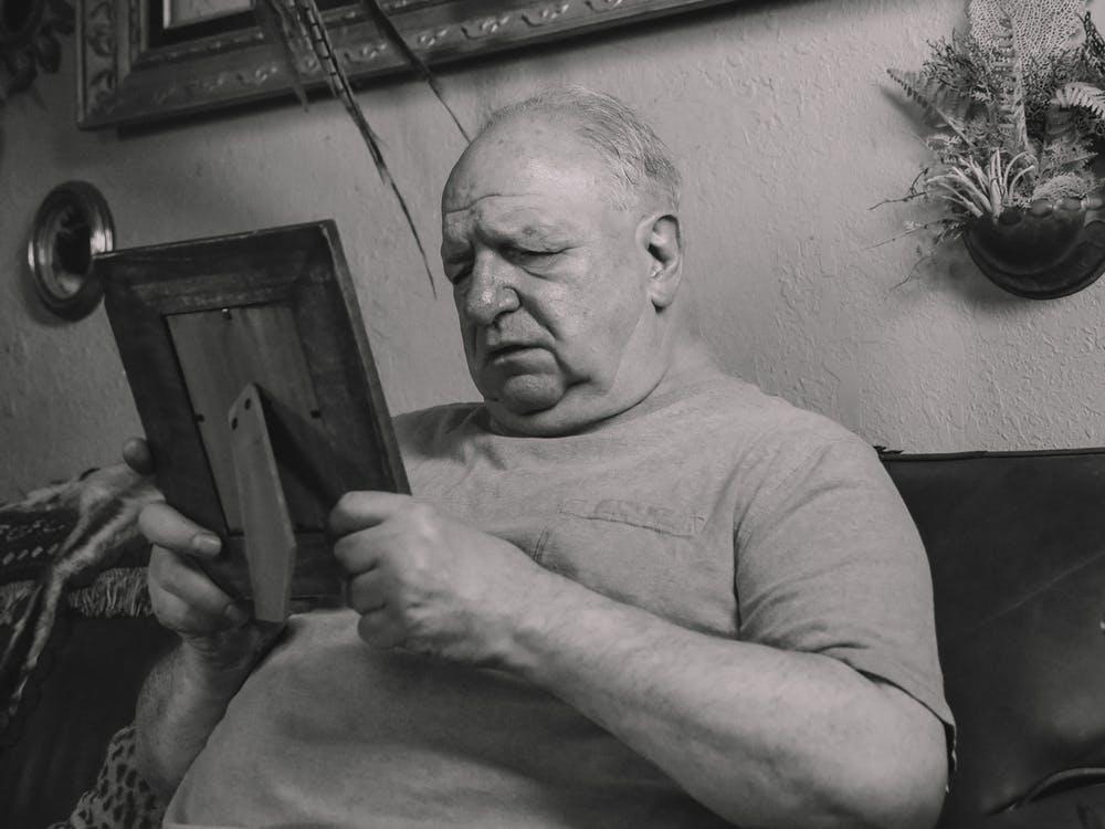 Free A Grayscale Photo of an Elderly Man Holding a Wooden Frame Stock Photo
