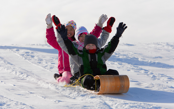 children sledding down snow mountain