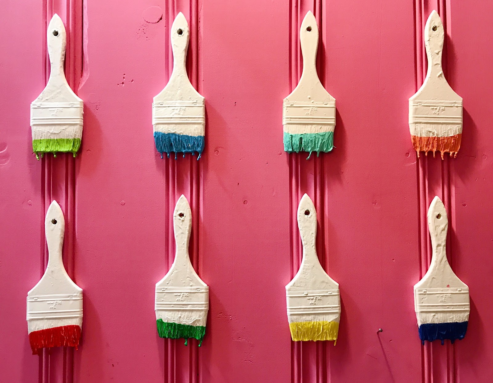 Paint brushes laid out, dipped in various colors. 