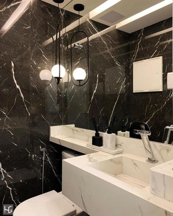 Banheiro com pia revestida de porcelanato marmorizado branco, parede revestida de porcelanato marmorizado preto