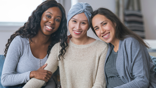Three women sitting side-by-side smiling