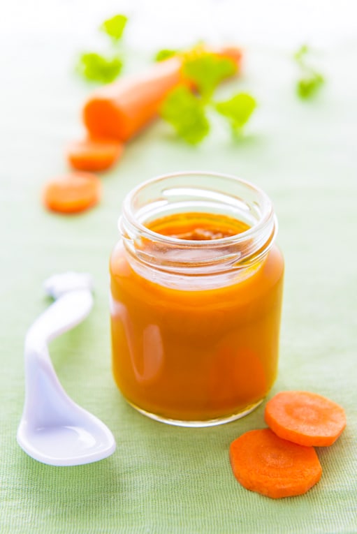 carrot puree served in a glass jar against a green background