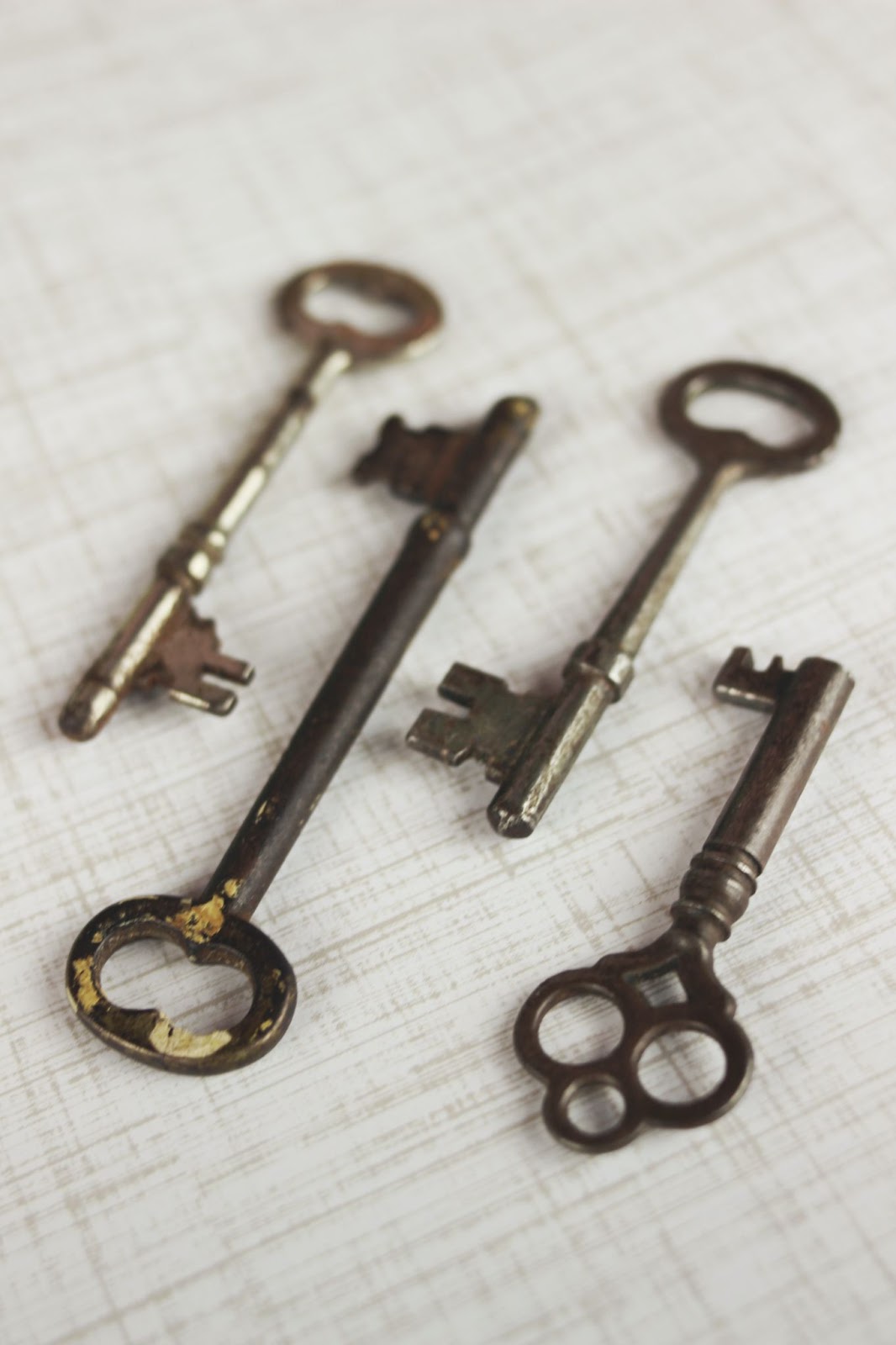 four antique keys lying on a crosshatched background.