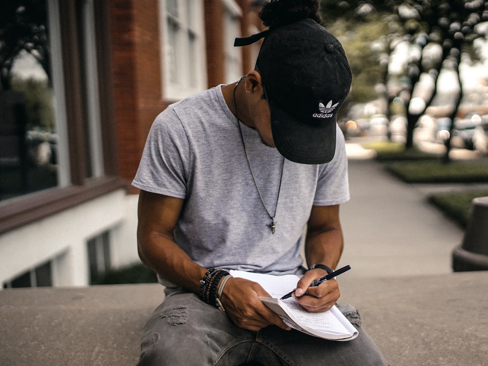 Menino sentando escrevendo em um caderno 