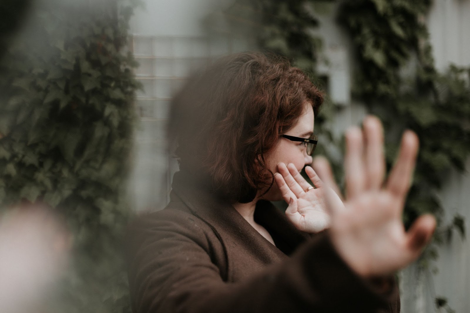 A slightly out of focus shot of a woman with her head turned and her hands raised, as if refusing something.