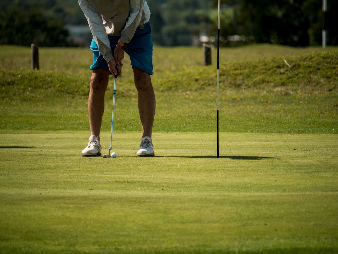 man in white shirt and blue shorts playing golf during daytime