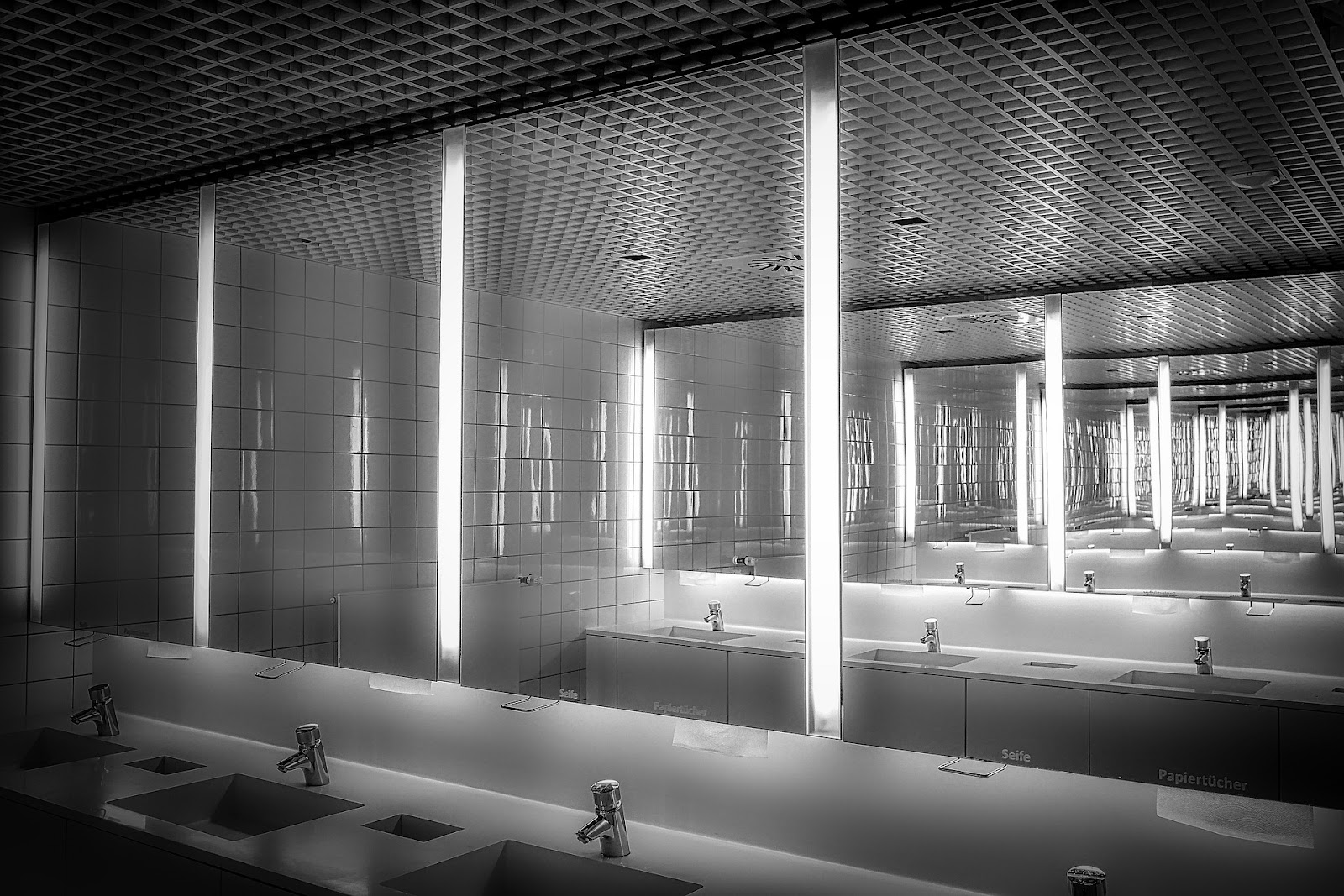 Two bathroom mirrors make what appears to be a never ending reflection of each other, similar to the effects of an infinity mirror.