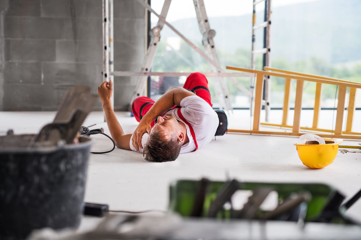 Construction worker lying on the floor with a broken shoulder