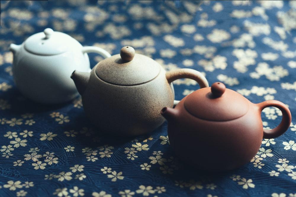 three assorted-color teapots