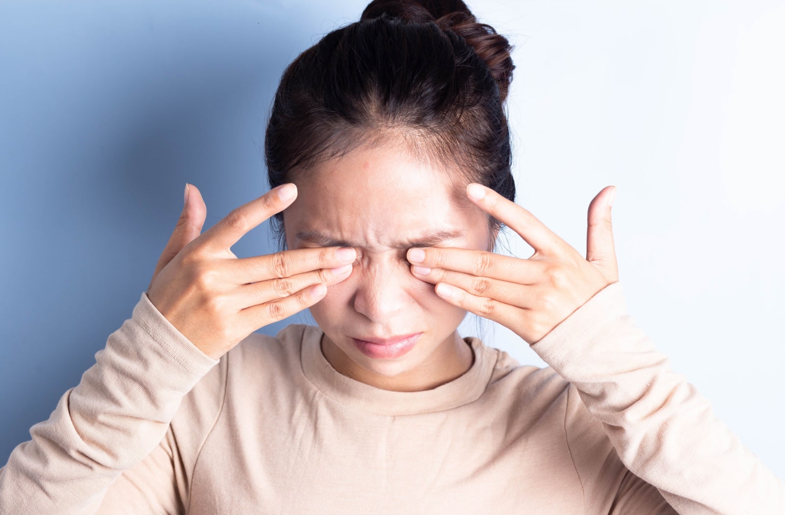 A woman rubs her irritated eyes.