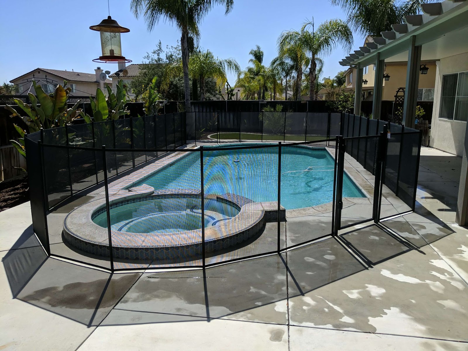 black mesh removable pool fence installed surrounding a swimming pool