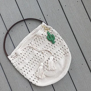 crochet tote with tassels on wooden deck