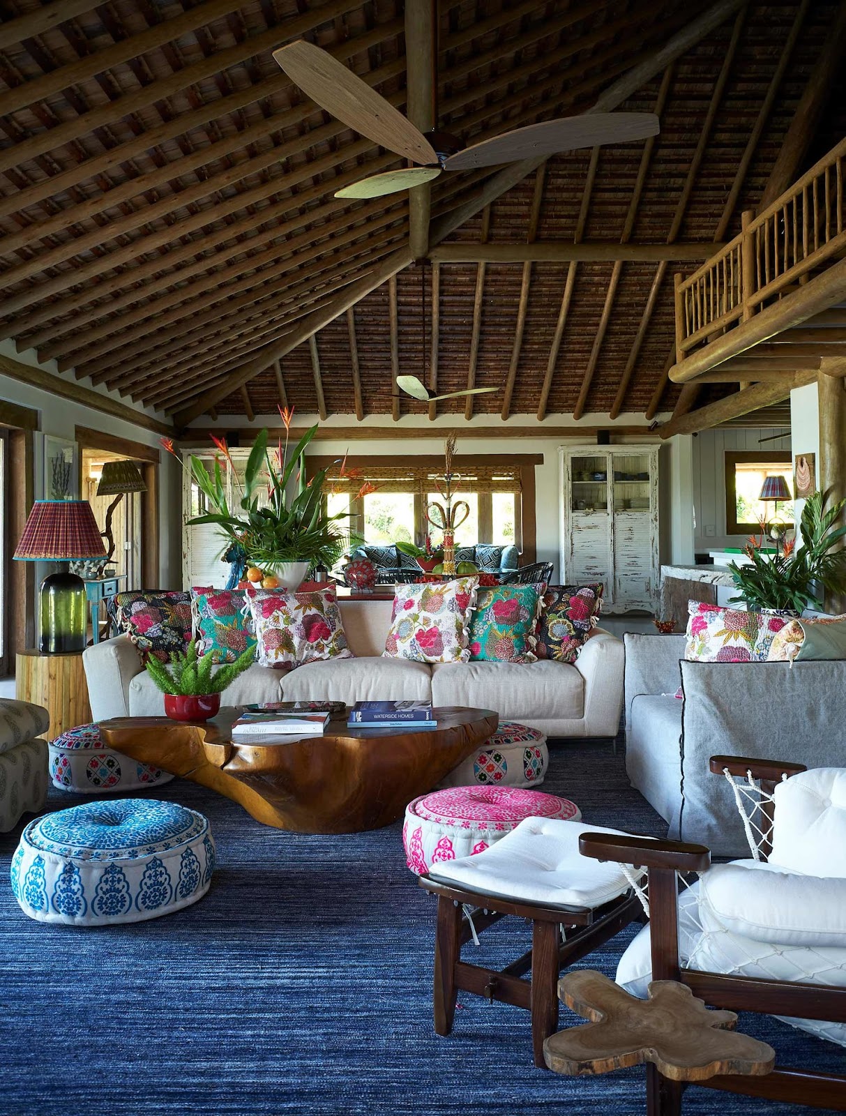 Sala com tapete azul, moveis de madeira e almofadas florais Sig Bergamin