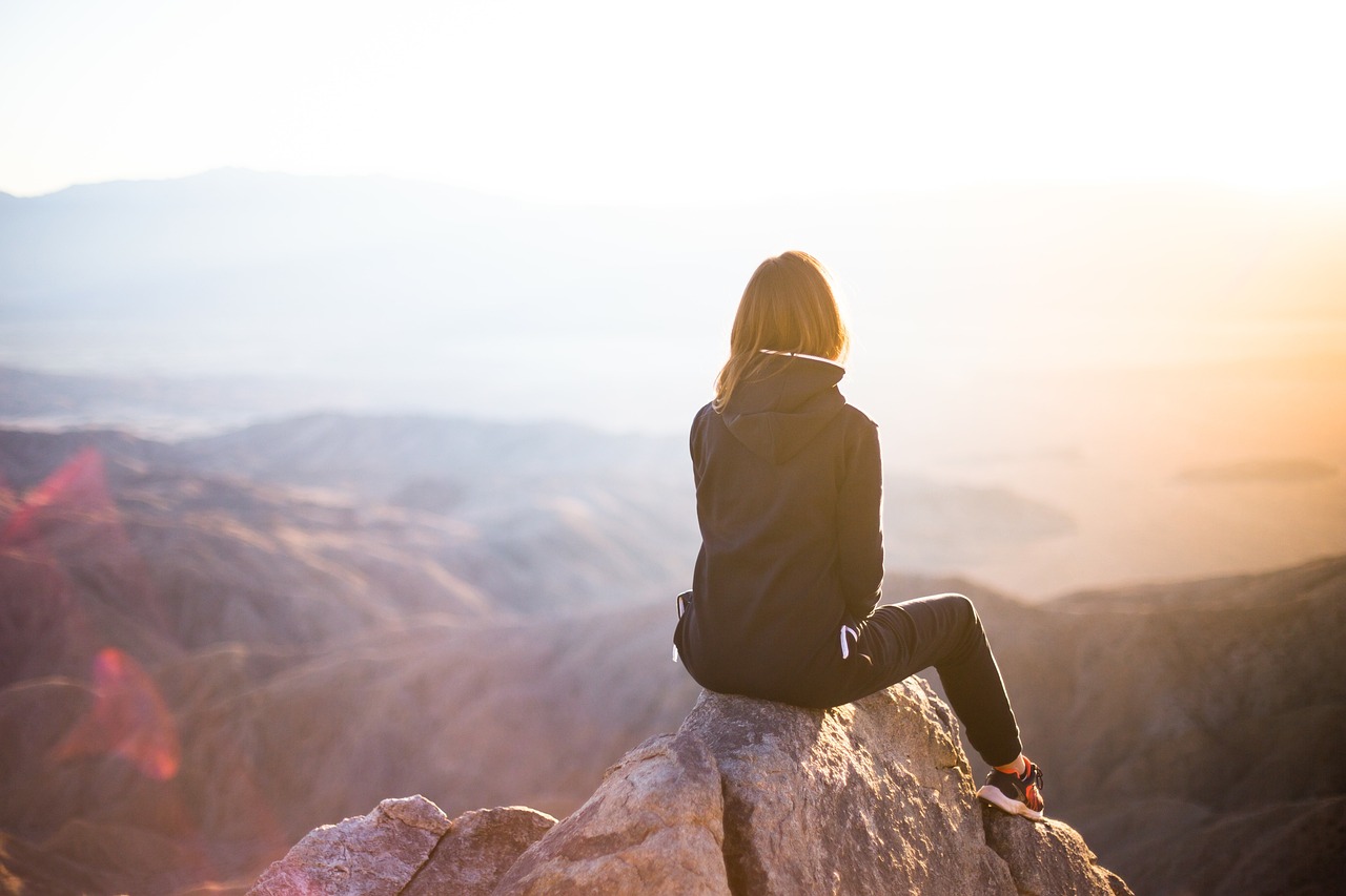 woman sitting alone at the top of the hill looking at the view