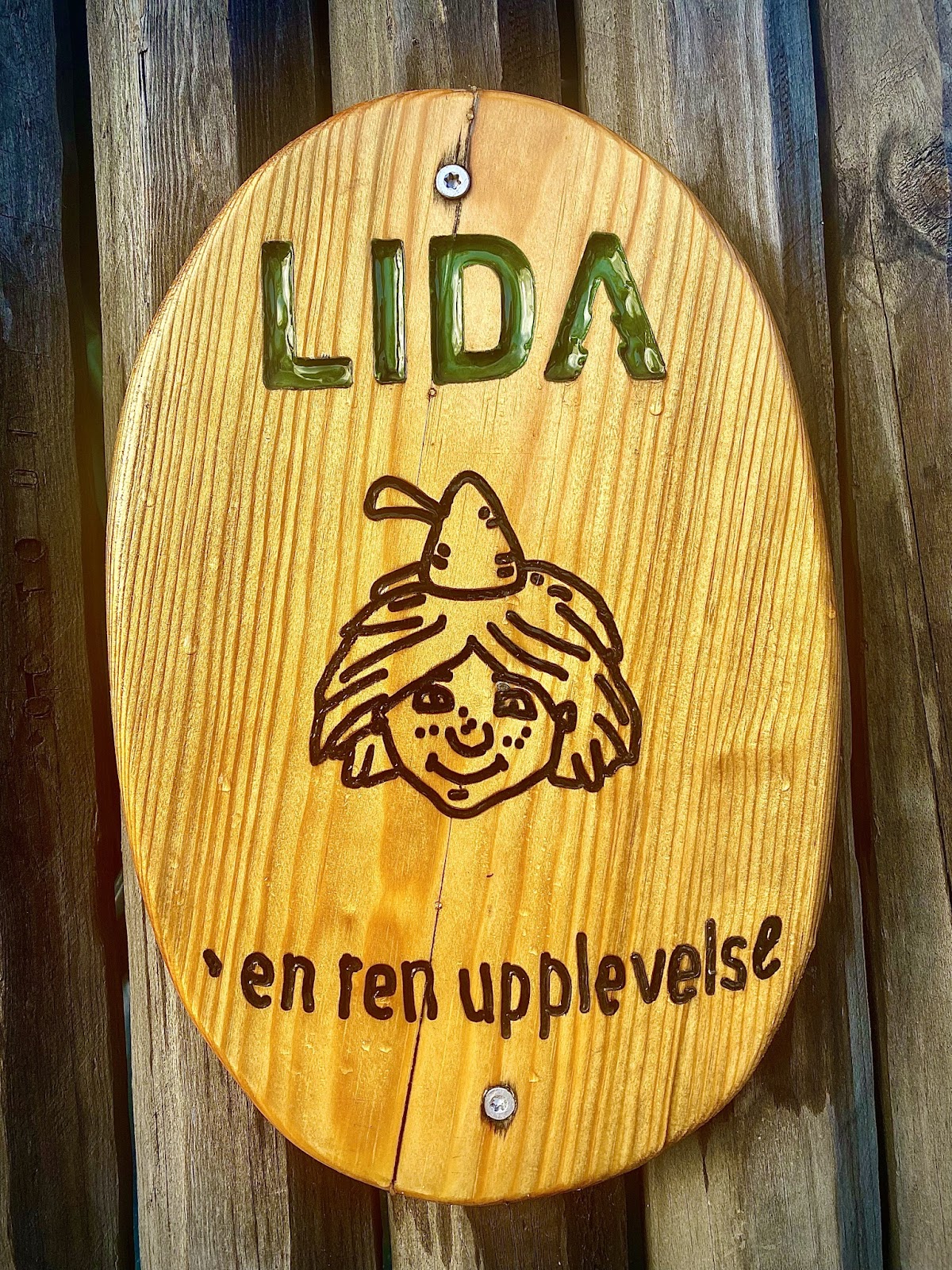en träskylt med Skogsmulles ansikte och texten: "Lida - en ren upplevelse"