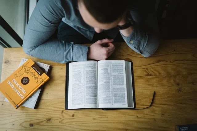 A photo of man seated in his study desk studying the Bible