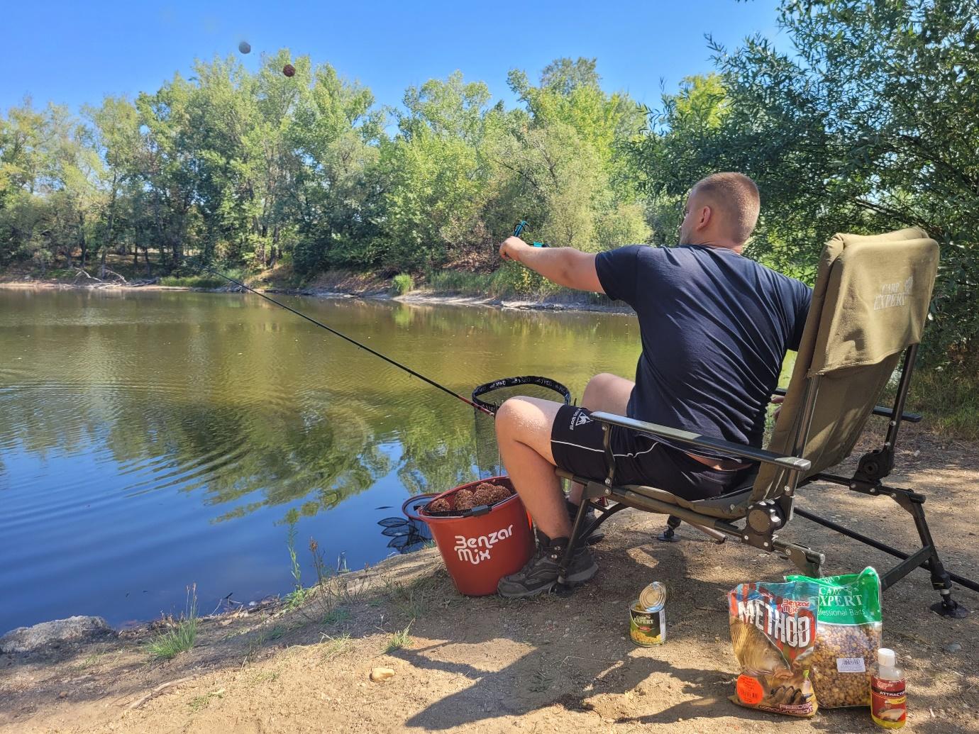 A person sitting on a chair by a lakeDescription automatically generated with medium confidence