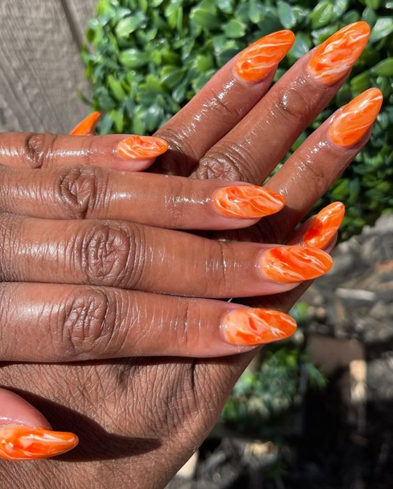 Close up view of a lady rocking an orange  marble nail