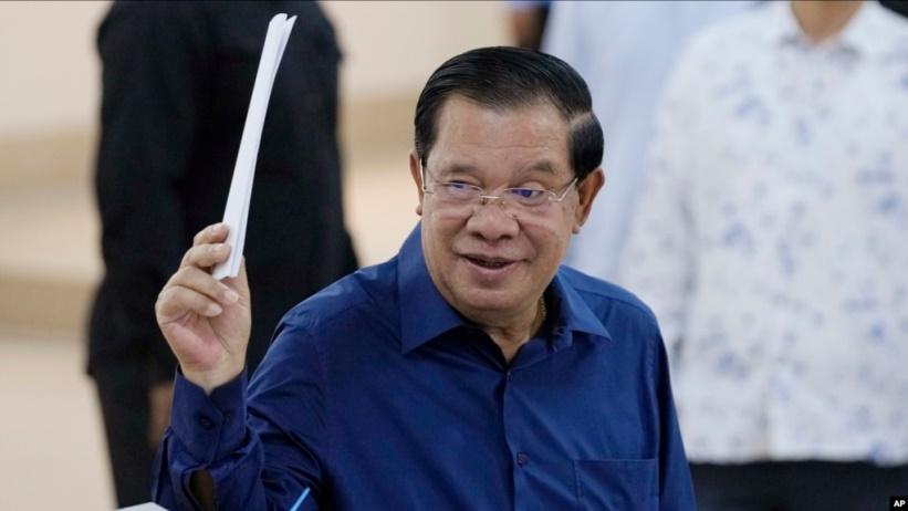 Thủ tướng Campuchia Hun Sen cầm lá phiếu trước khi bỏ vào hòm phiếu tại một điểm bầu cử ở Phnom Penh hôm 23/July 23. Ông Hun Sen nói sẽ trao quyền cho con trai Hun Manet vào tháng tới.