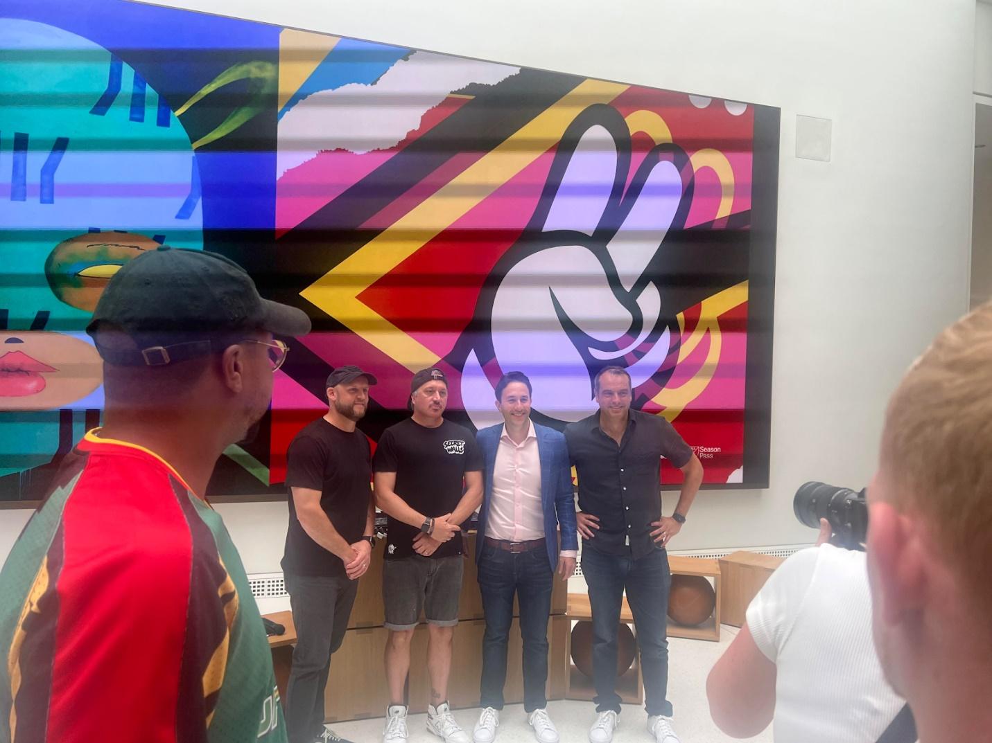A group of men standing in front of a colorful wall

Description automatically generated