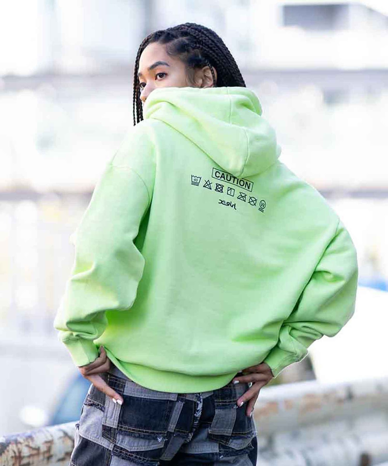 Cozy hoodie with X-girl face logo tag graphic on front and industrial-style graphics across upper back.