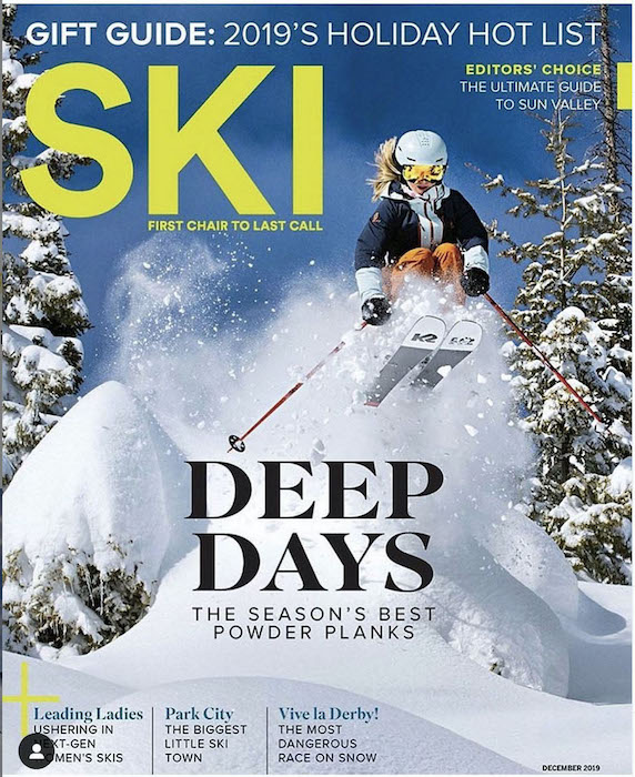 A cover image of a skier jumping through bushes covered in a few feet of soft powder, taken by Hillary Maybery.