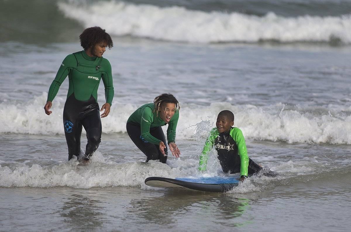 A group of people surfing in the sea  Description automatically generated with low confidence