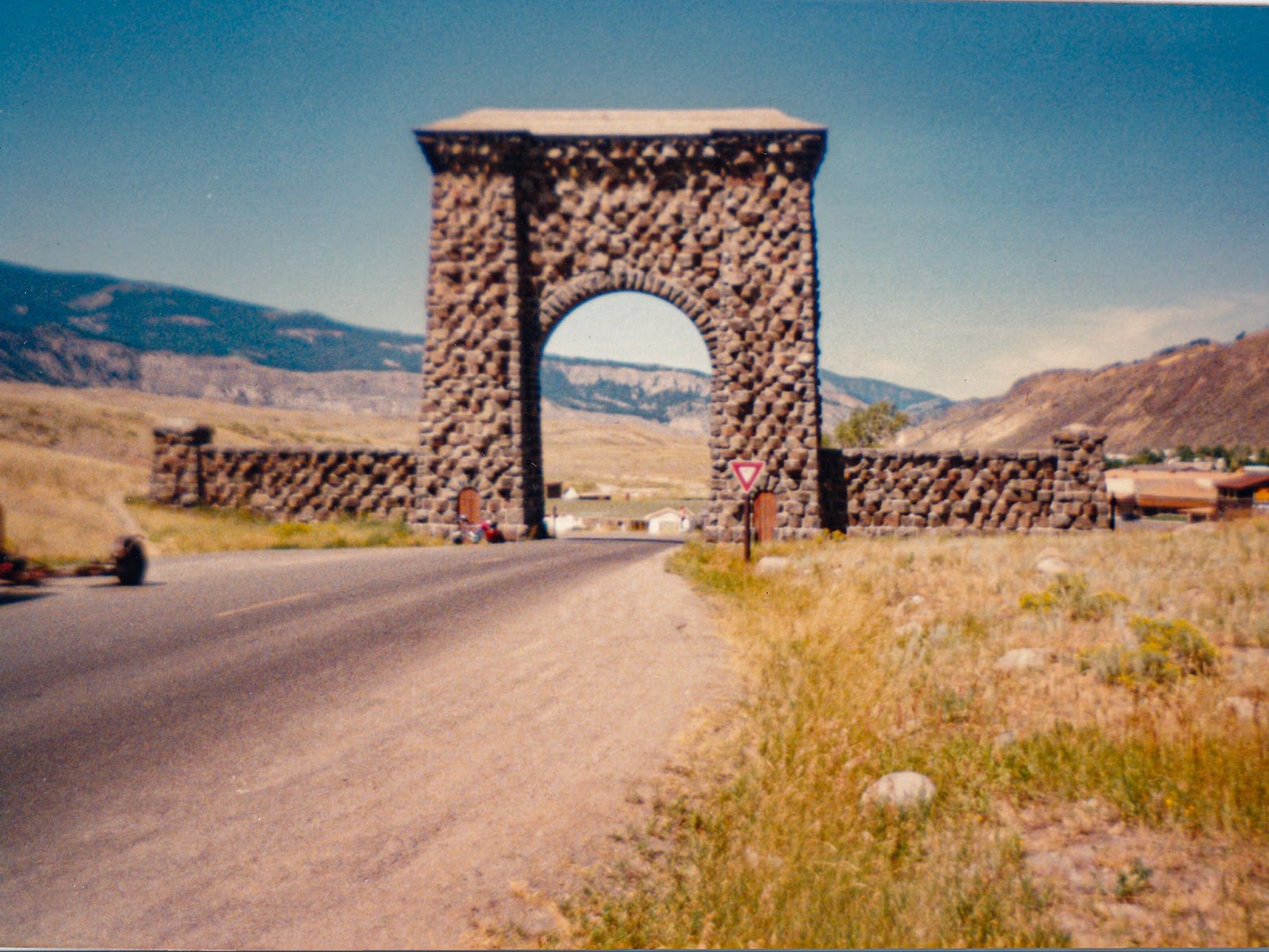 A large fieldstone gate across a small asphalt road. 