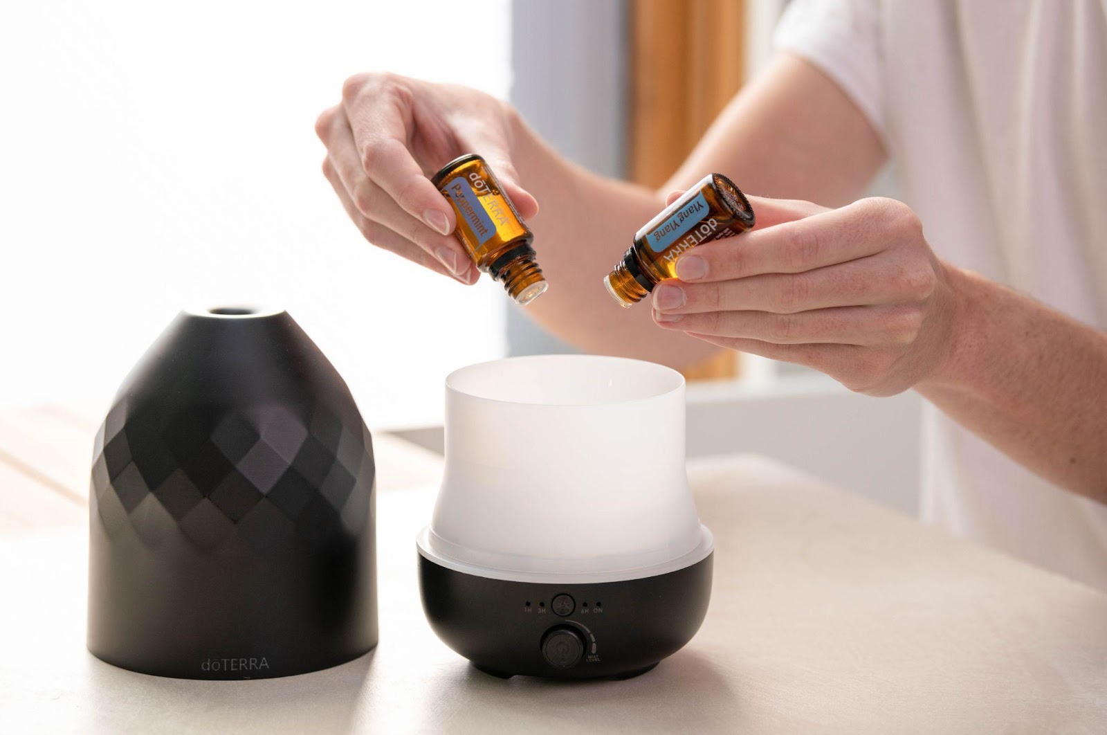 A woman puts essential oils into a diffuser. This article covers tips to pick the right Birthday hampers for your co-worker.
