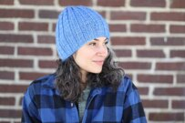 woman wearing light blue hat in front of brick wall