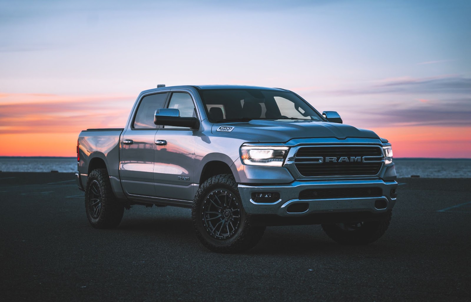 A Ram 1500 truck at sunset near a body of water