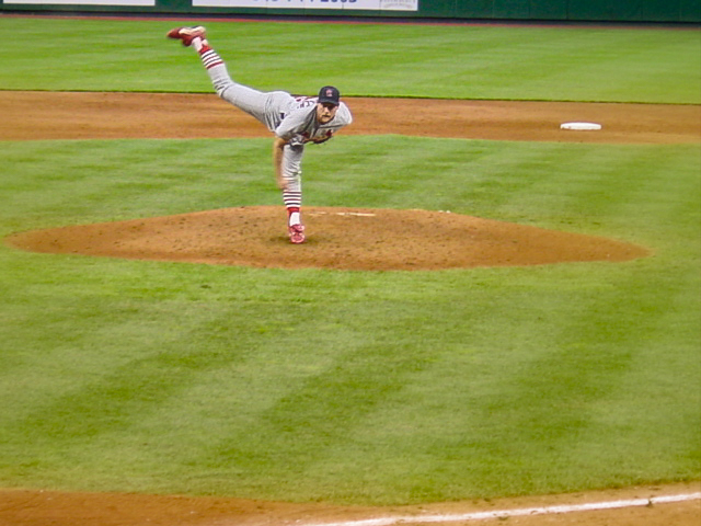 The pitcher releases the ball and his leg extends above his head. 