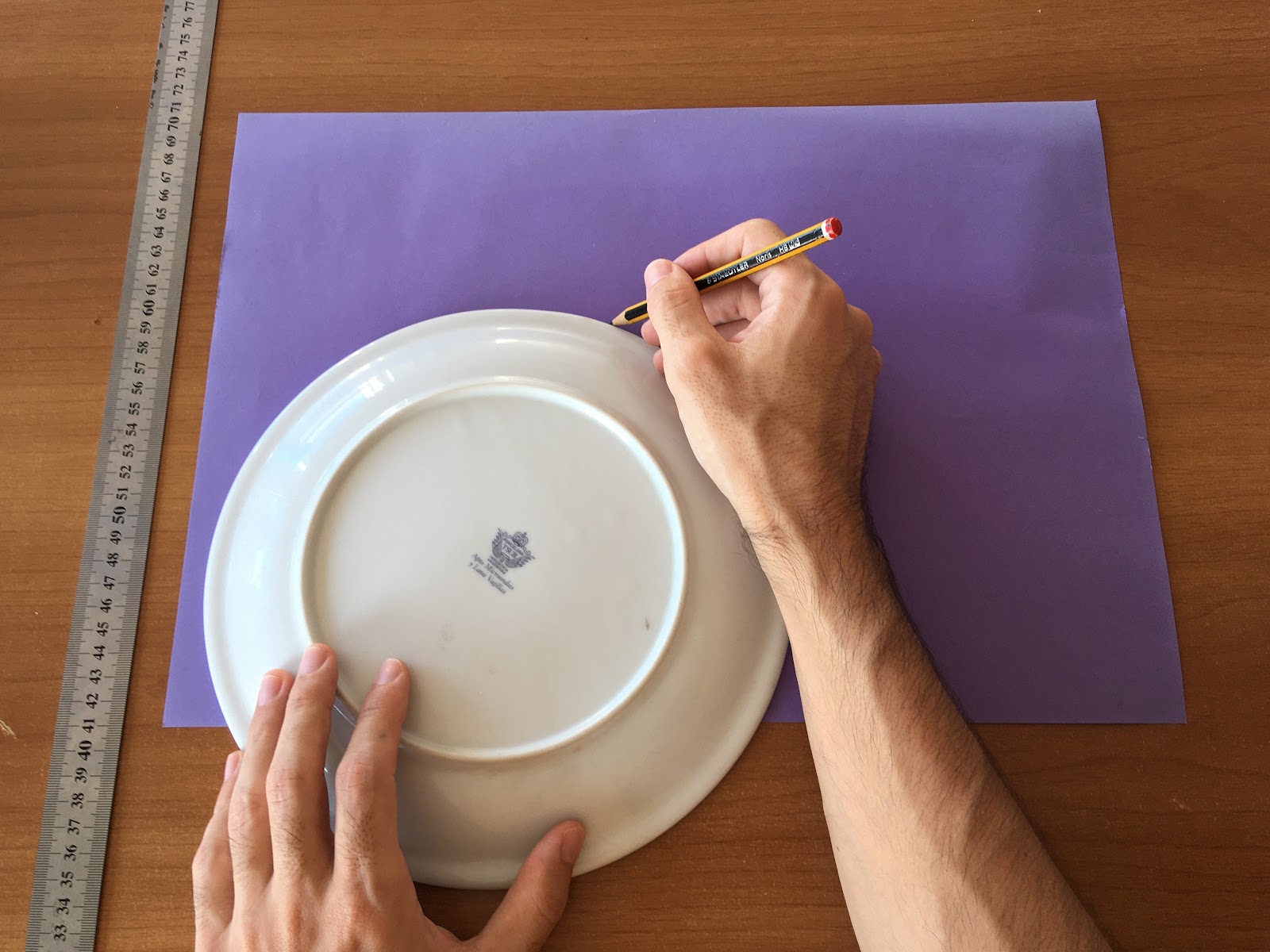 Trazado de un arco en lápiz sobre la cartulina de color utilizando el contorno de un plato.