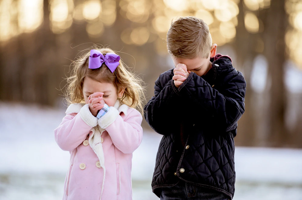 a little boy and a girl praying 