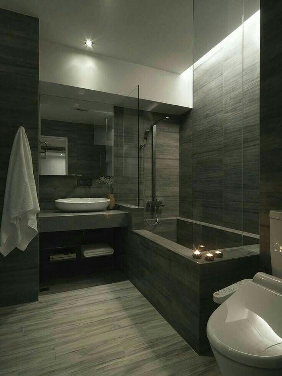 32 Inspirações de banheiros com porcelanato amadeirado - banheiro com revestimento amadeirado escuro por todo banheiro: paredes, bancada da pia, banheira e piso.