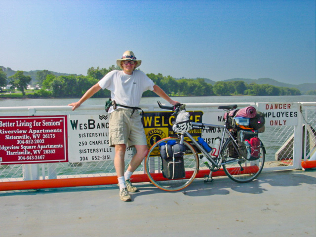 Cyclist on the rail of a boat beside his bicycle. 